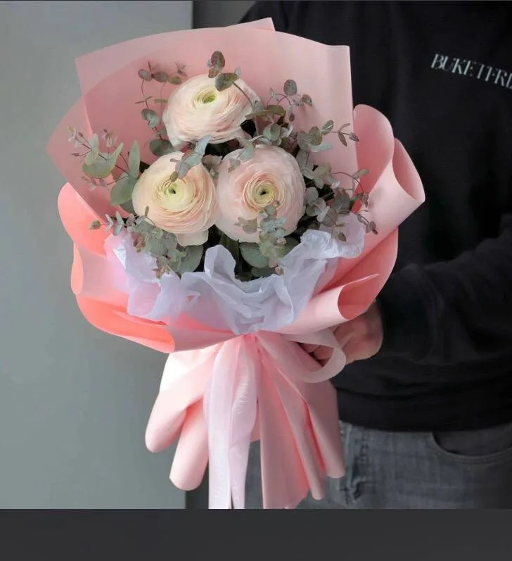 Üç krem ranunkulus və evkalipt yaşıllığı